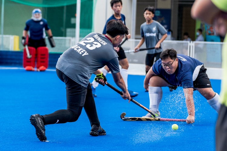 northland secondary school student takes a shot but st hilda's player blocks it bravely with stick on the ground