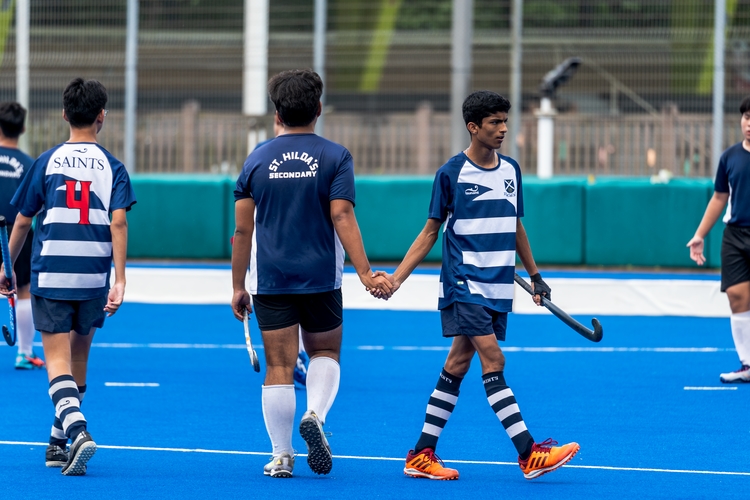 match between st andrew's and st hilda's. Two players shaking hands but no eye contact