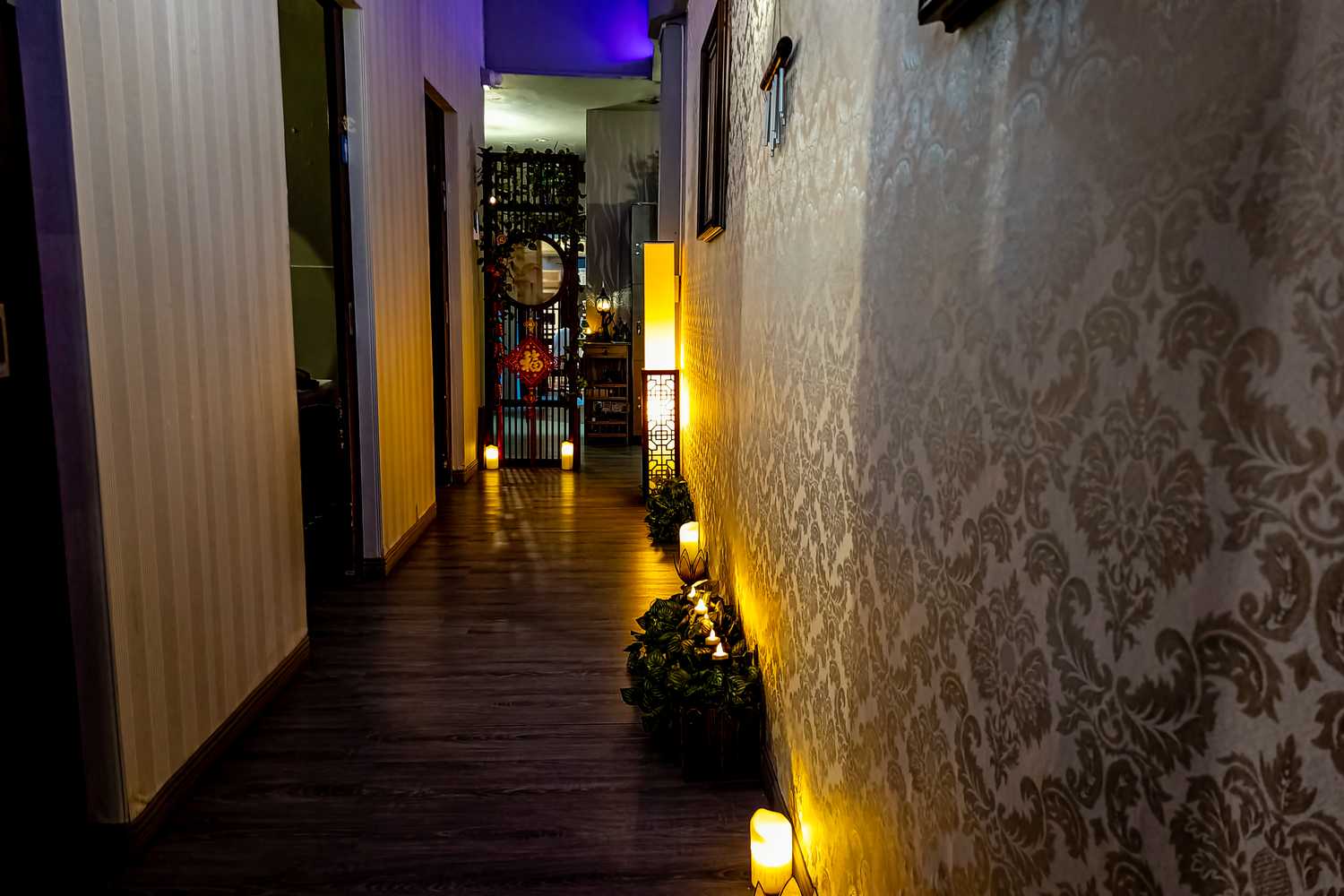 a massage parlour hallway with dimly lit lights and ornamental designed wallpapers