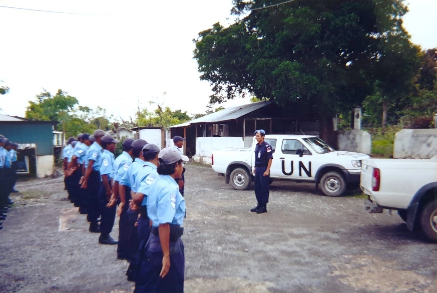 SI Farik on the right side, facing a contingent of blue uniform wearing officers. Officers are facing the 3pm direction while SI farik is standing alone and facing the 9pm direction. 