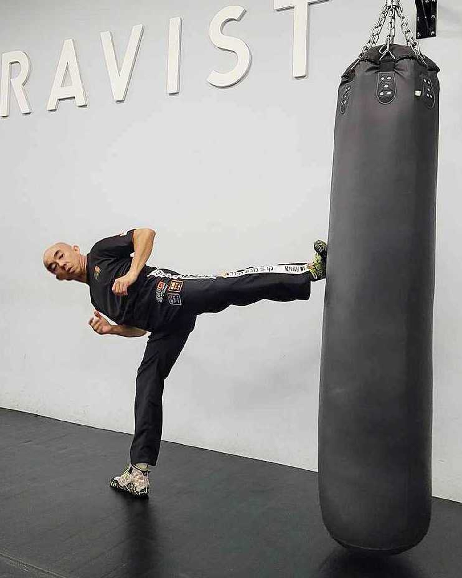 Inspector Tan Buck Song kicking a black punching bag in his gym. 
