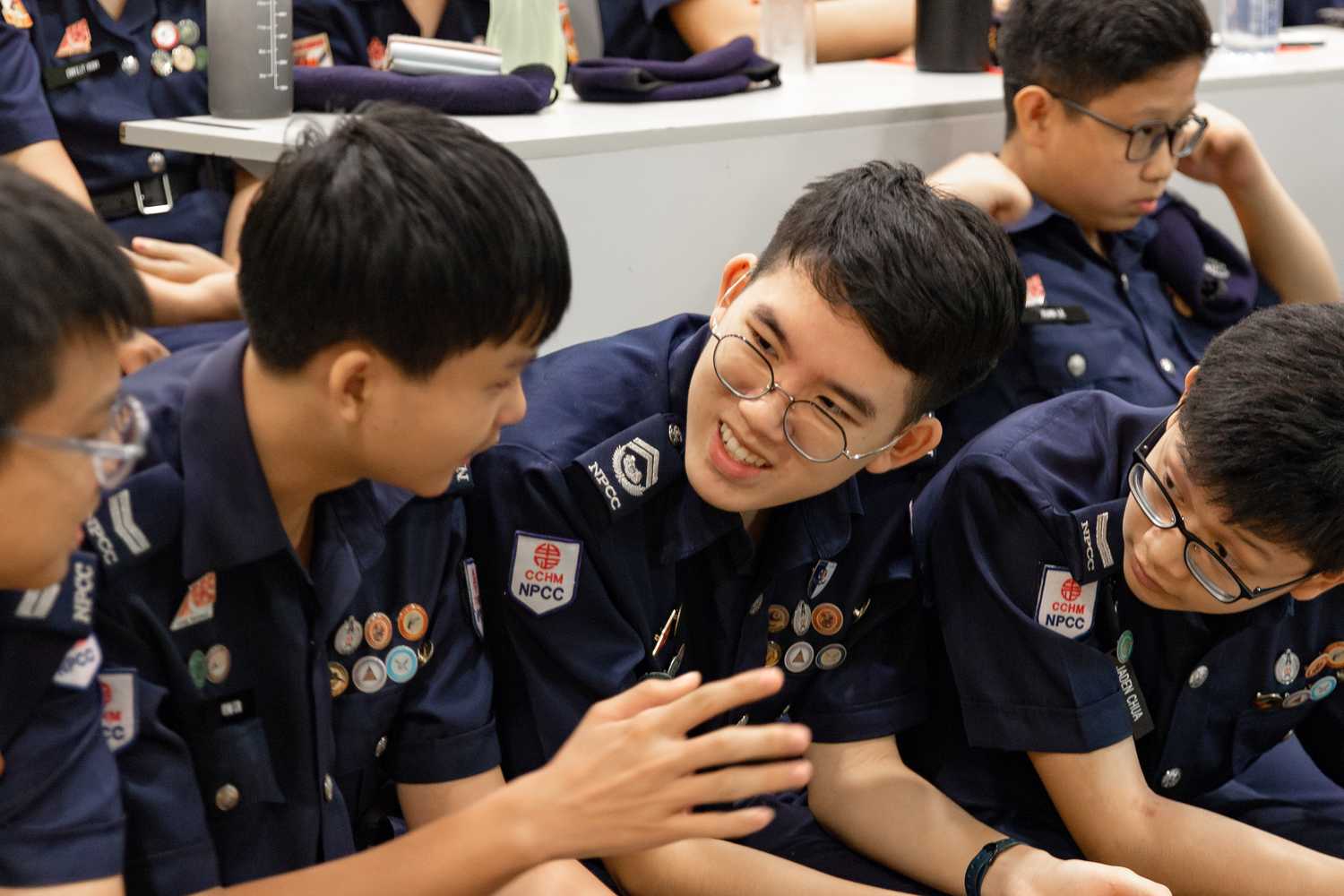 NPCC Cadets chatting with each other, one boy smiling at his friend, the latter telling him something. Both are engaged in conversation. 