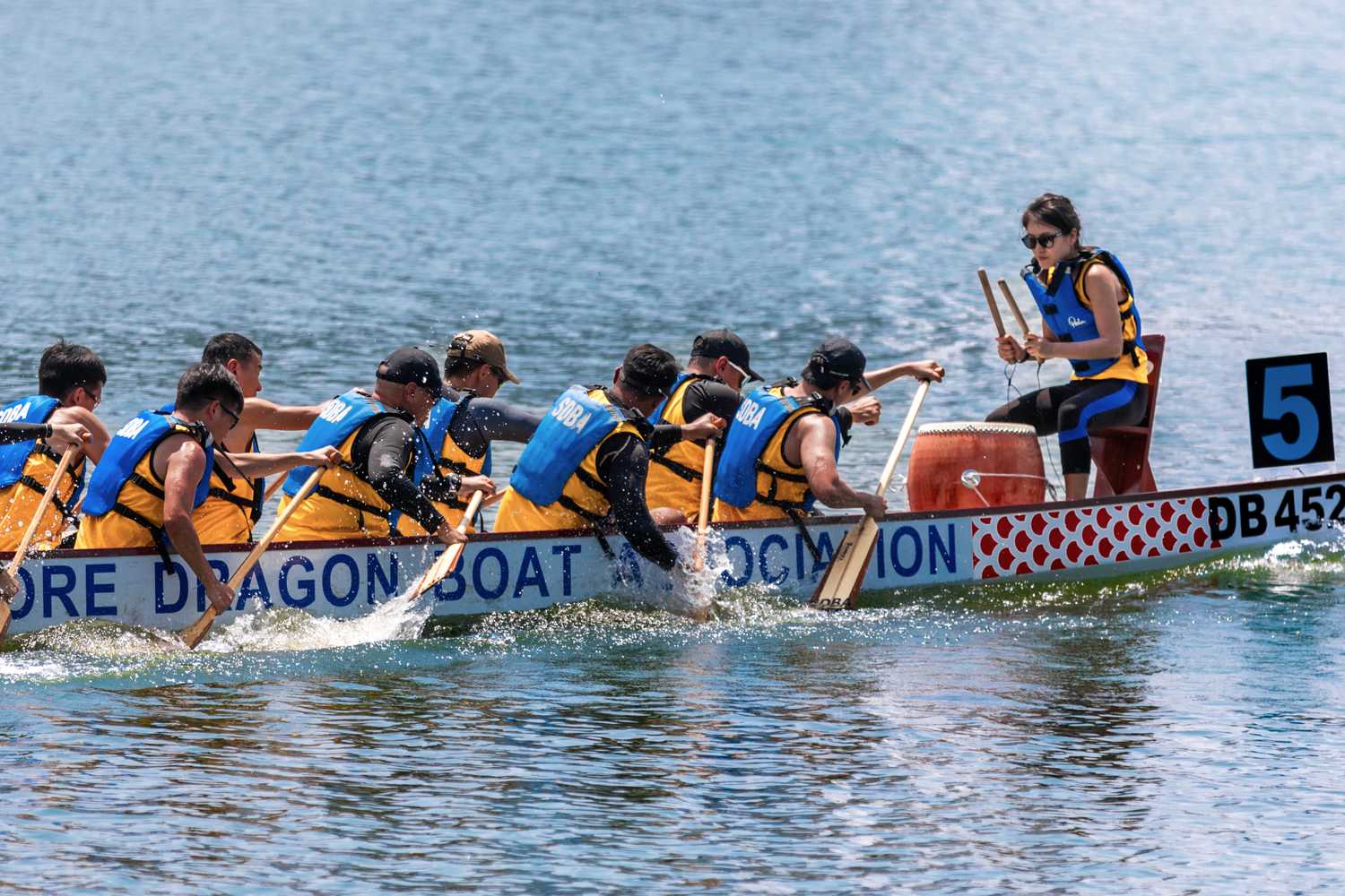 close up shot of a group of paddlers on one dragonboat out on the water listening to their drummer