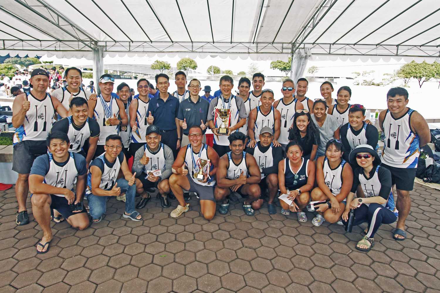 a team photo of two rows of people in white singlets and medals around their necks