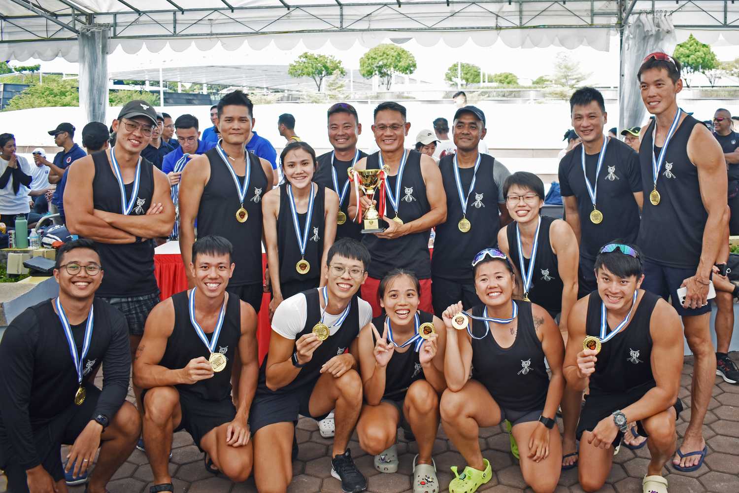 a team photo of two rows of people in black singlets and medals around their necks