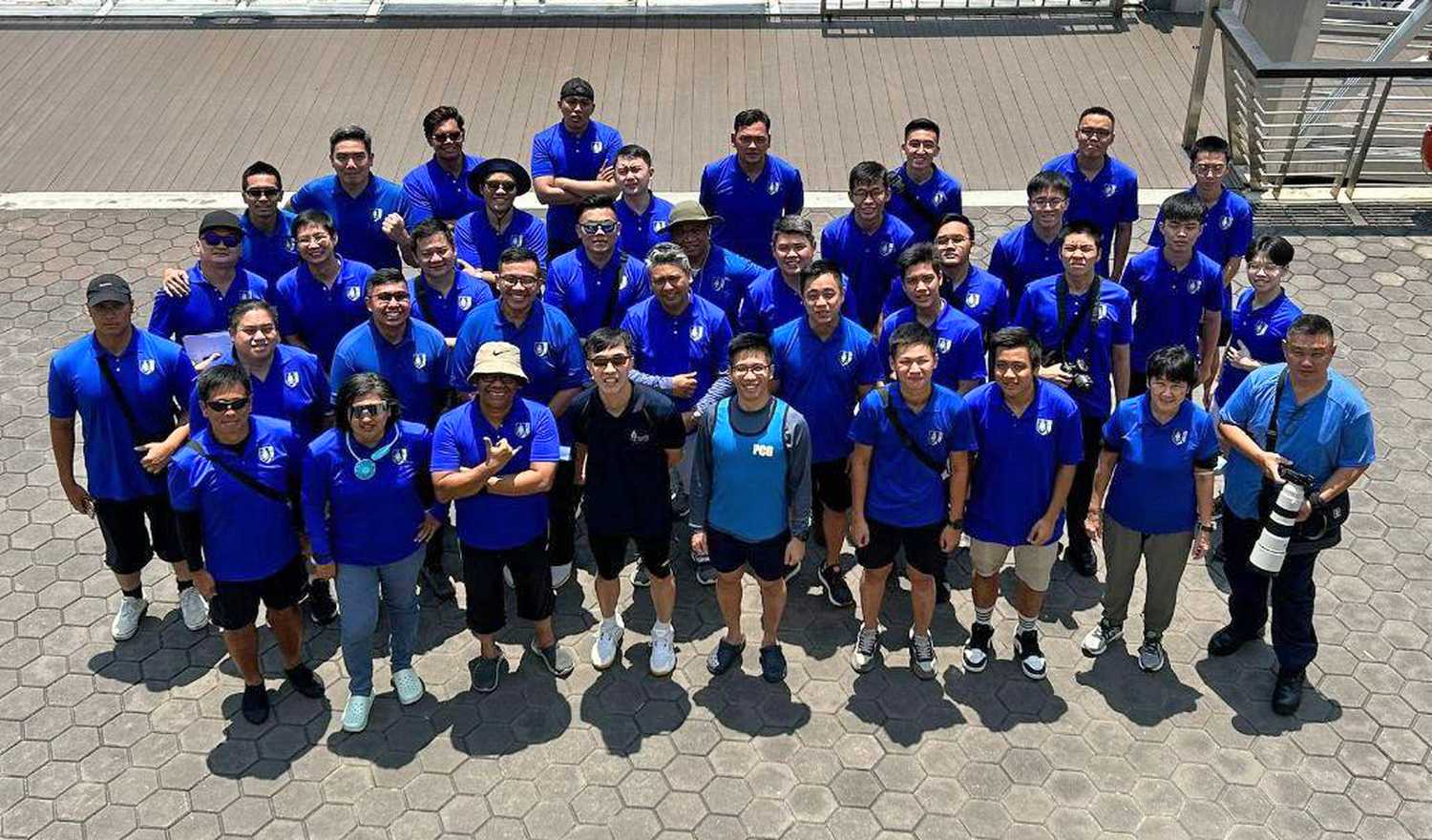 a team photo from top view of a group of people in blue shirts, standing and looking up at the camera