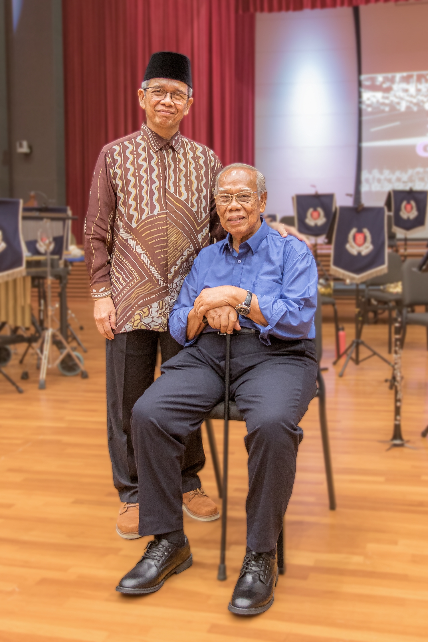 Mr Mohamed Salleh Bin Kandar is seated and his son, Mr Zaini Bin Mohamed Salleh, is standing behind him.