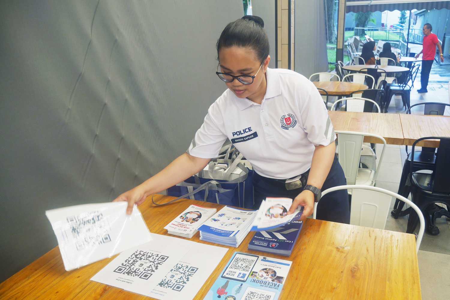 An officer preparing for the Coffee with a Cop event by arranging pamphlets.