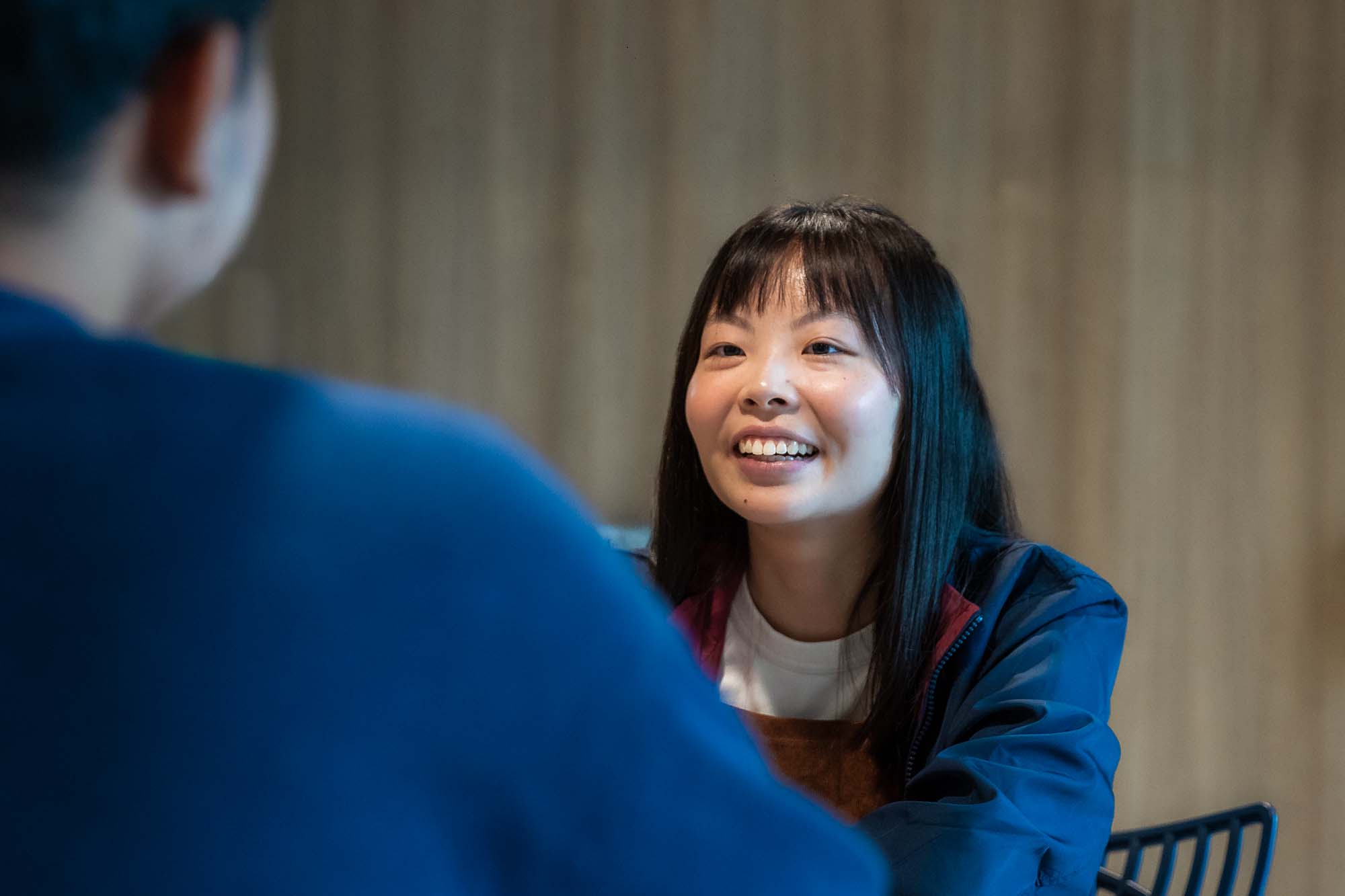 A profile shot of Amanda Wong shows her listening to another person during a conversation.