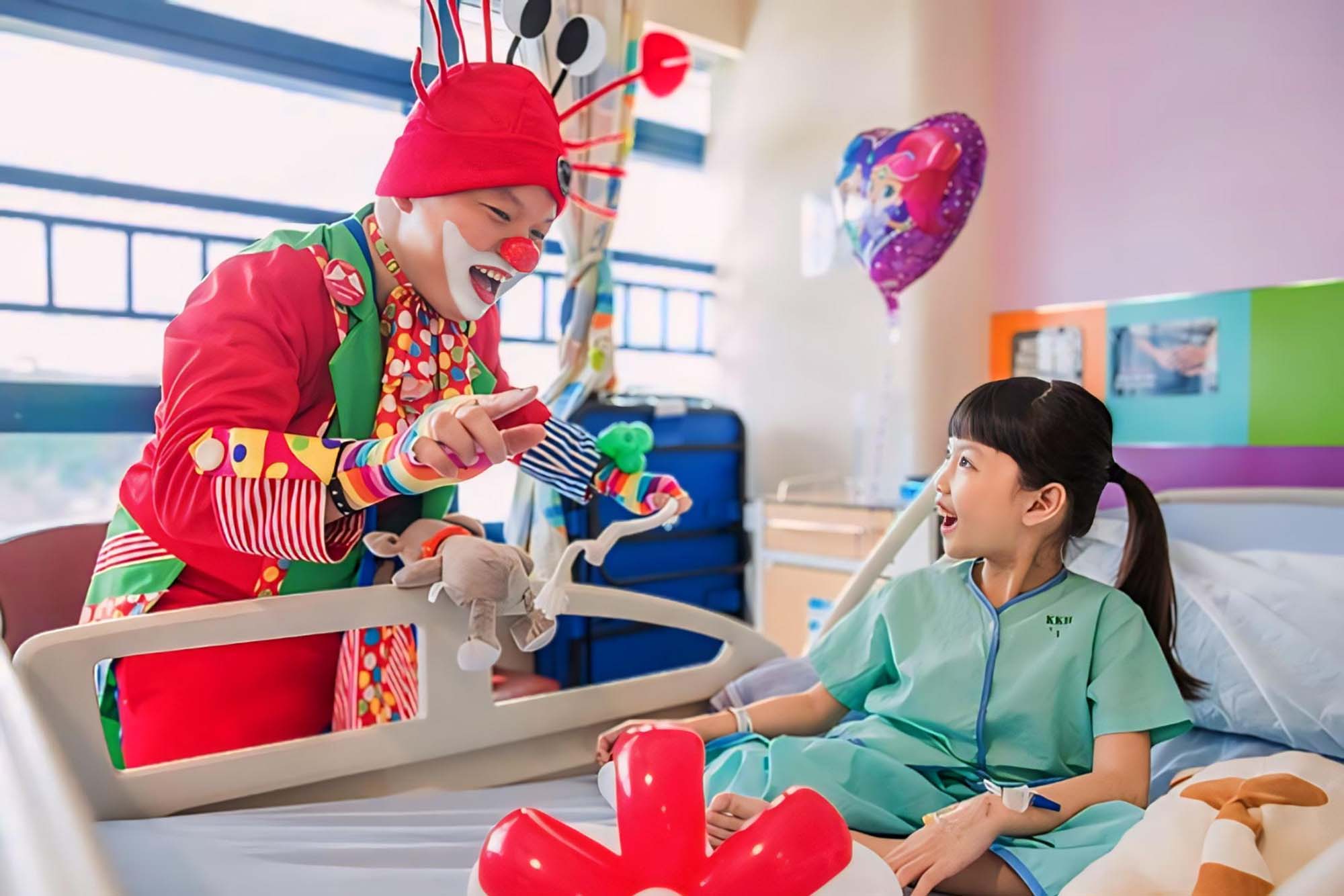 a clown entertaining and making a young female hospitalised patient laugh