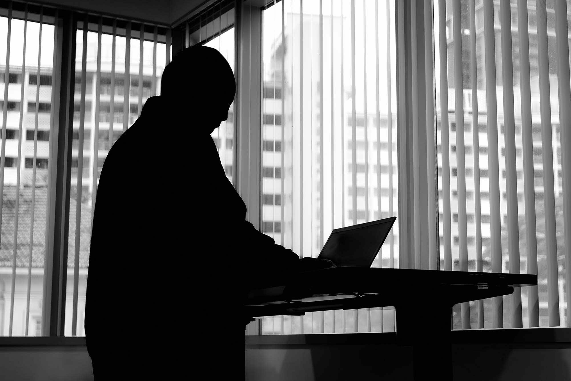 photo of a silhouette of a male figure next to a window panel in an office environment