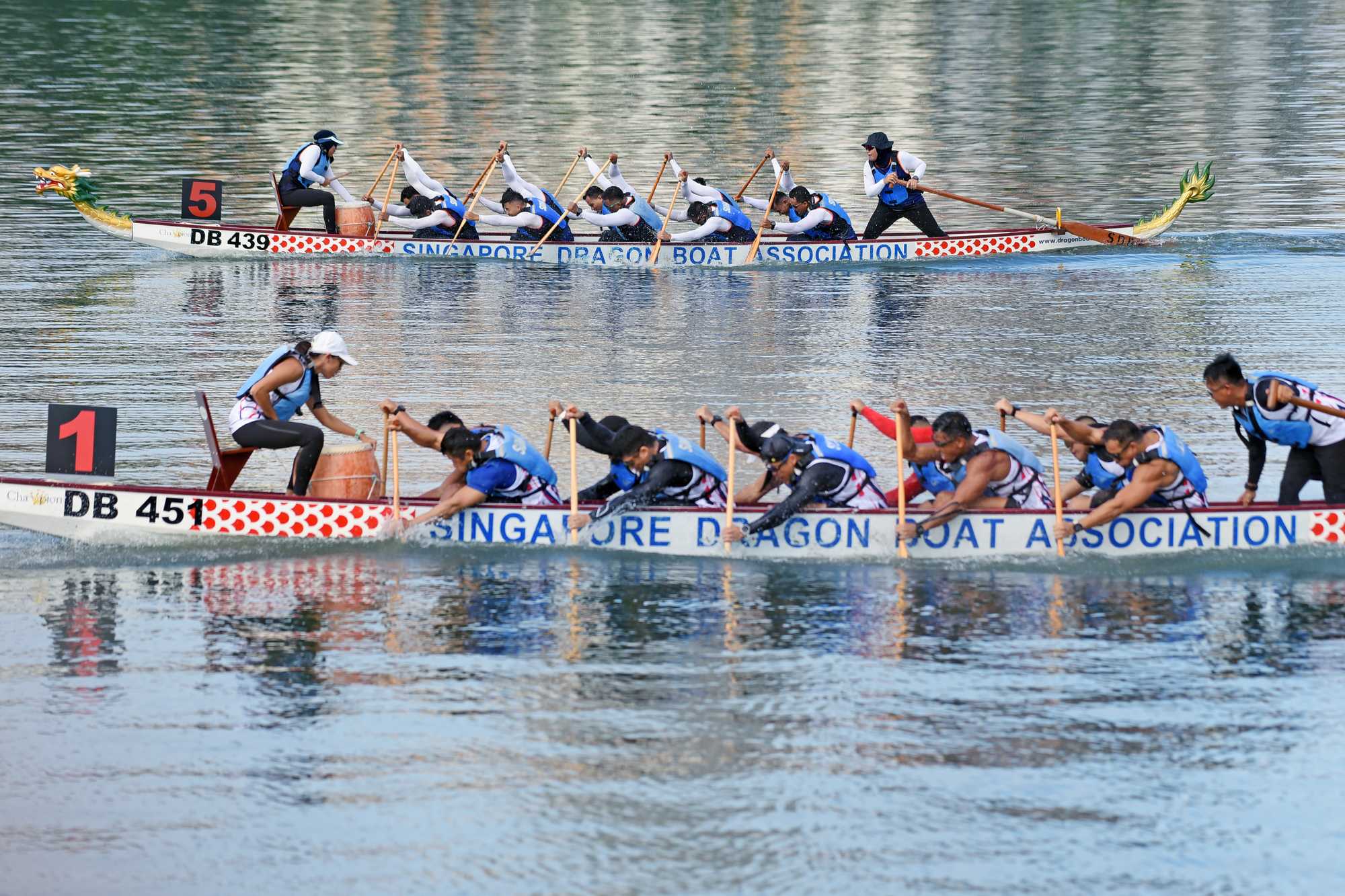 dragonboaters wearing dark blue rowing in unison towards the left direction