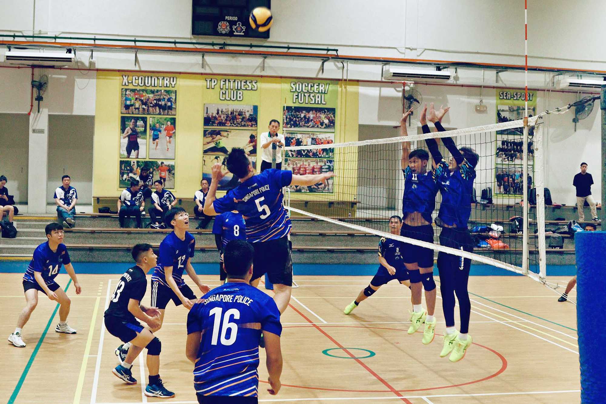 volleyball players wearing blue colour top jumping near the net to block a shot