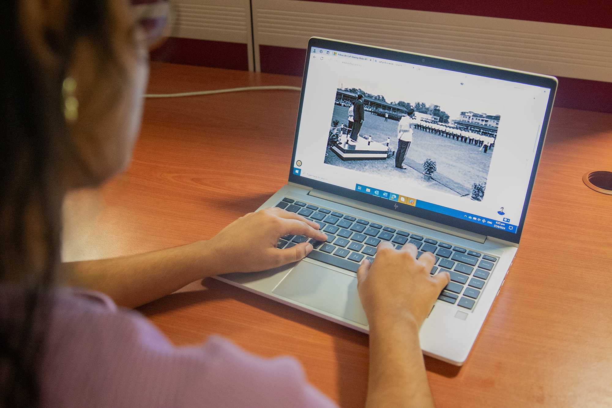 female subject typing on a laptop with the camera shot from her shoulder view 