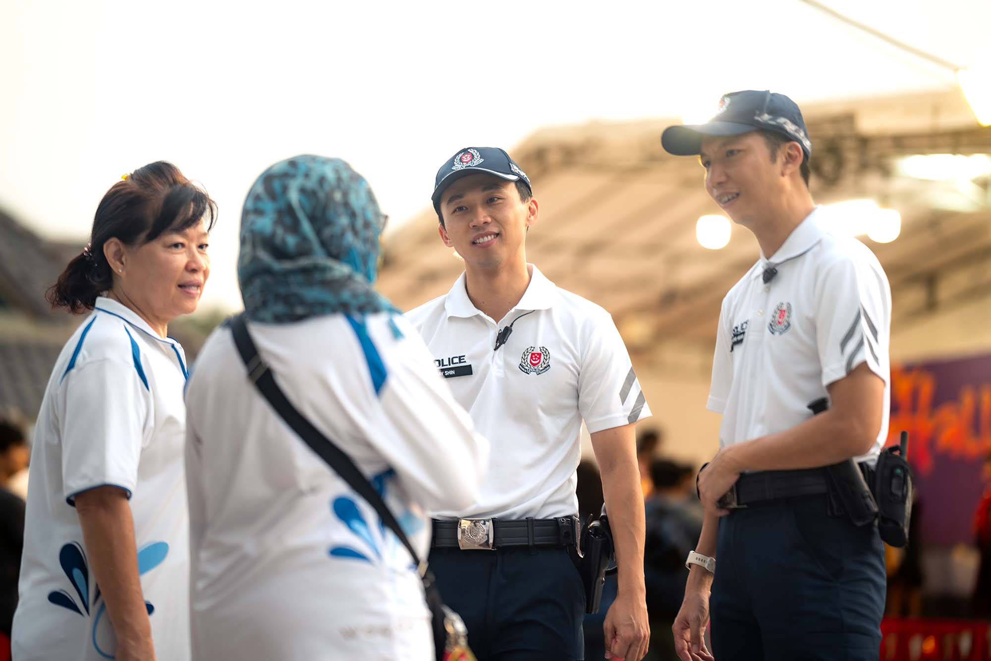 two cpu officers talking to two volunteers from PA. One is a malay lady with a blue tudung while another is an elderly chinese lady with a ponytail. event is being held at the rooftop of the shopping mall