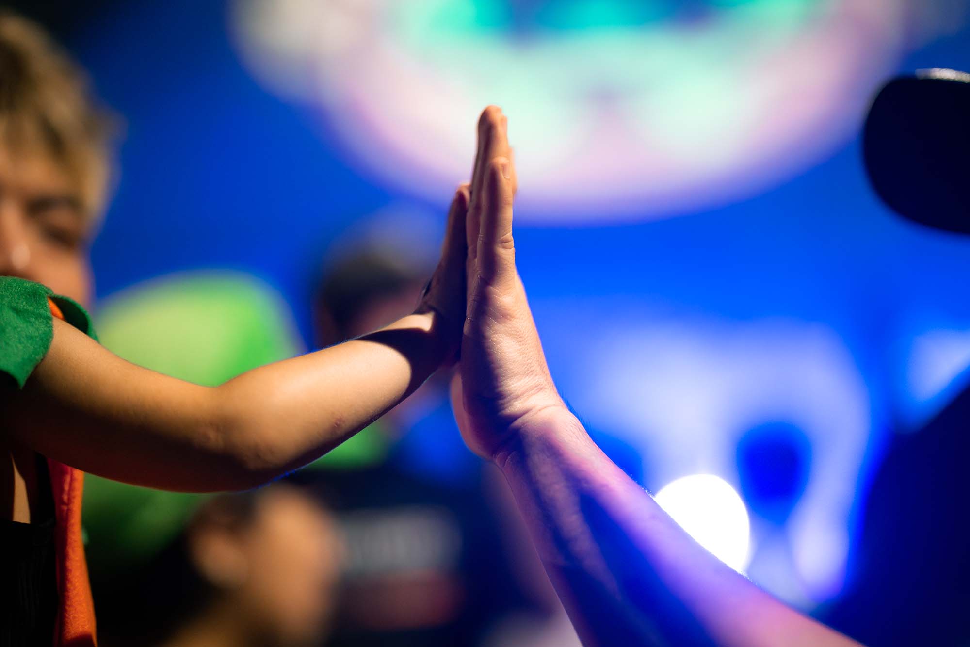 a photo of a kid high-fiving the police officer, with lights in the background creating a bokeh effect