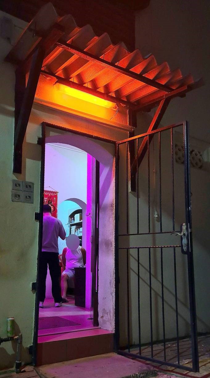 a saturated shot of the shophouse entrance which is dimly lit with a yellowish red tone and the inside is of pink colour lights