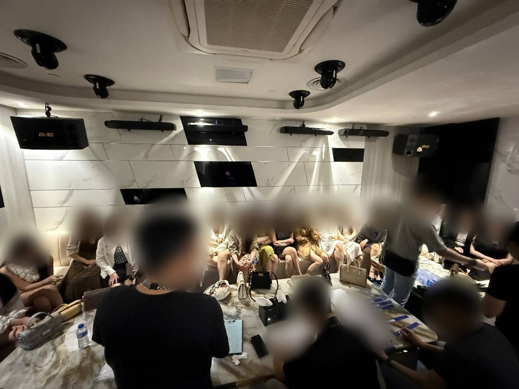 a shot taken inside a club, possibly the VIP room, where women are seen seated on a couch, with their faces blurred